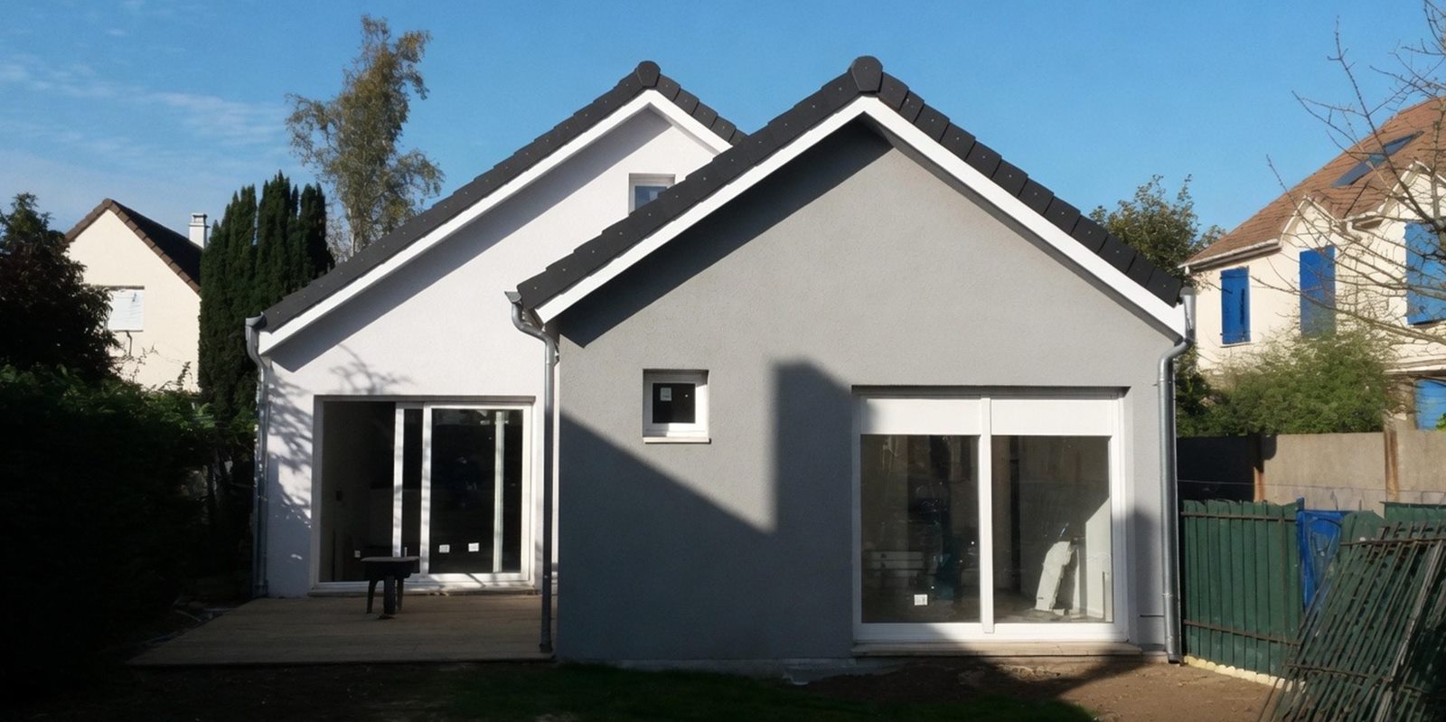 Maison neuve en ossature acier léger terminée, enduit gris et grande baie vitrée